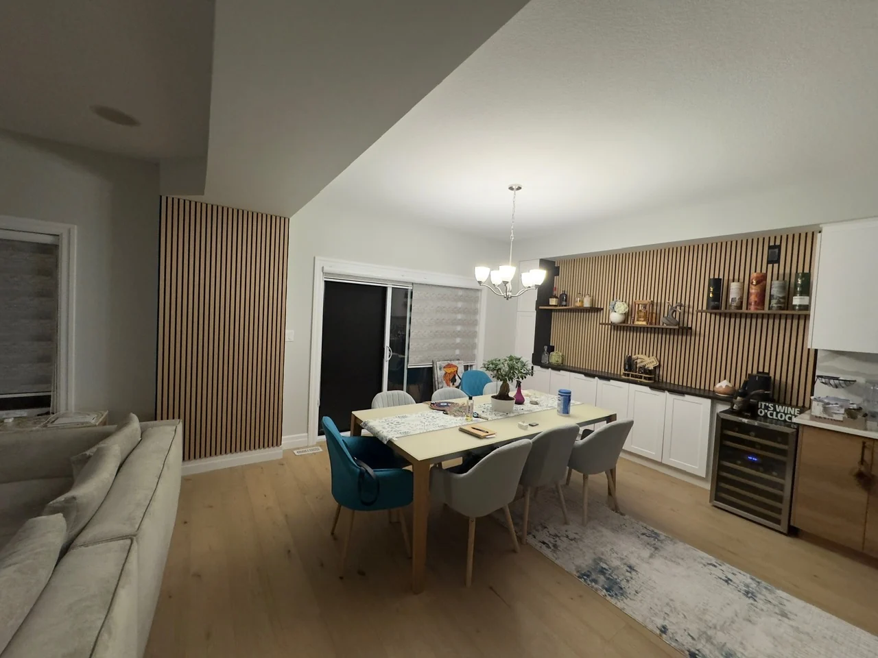 Dining area with wood-tone slat feature walls, shelving, cabinetry and light-tone flooring