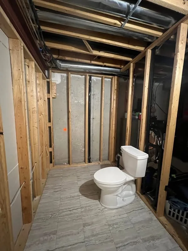 Bathroom during renovation with exposed wall framing and a toilet