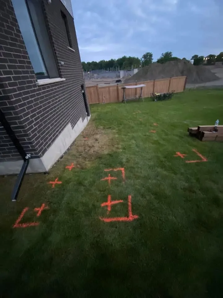 Deck layout marked on grass beside a brick home