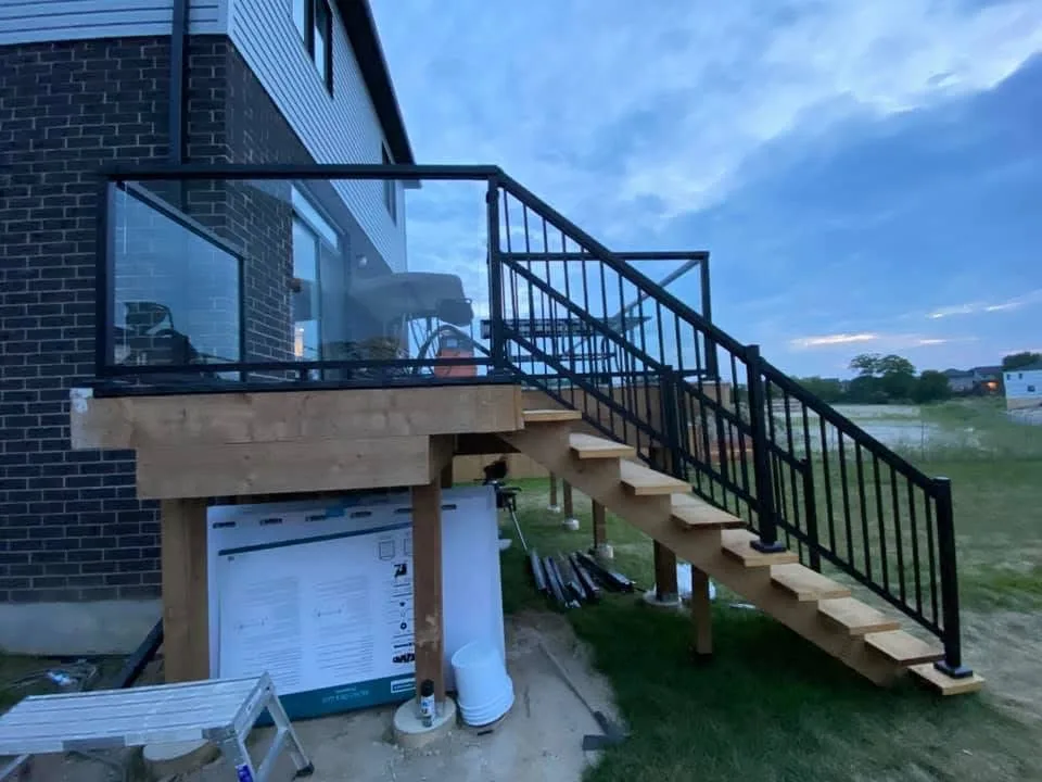 Black stair railings and glass panels installed on a raised wood deck