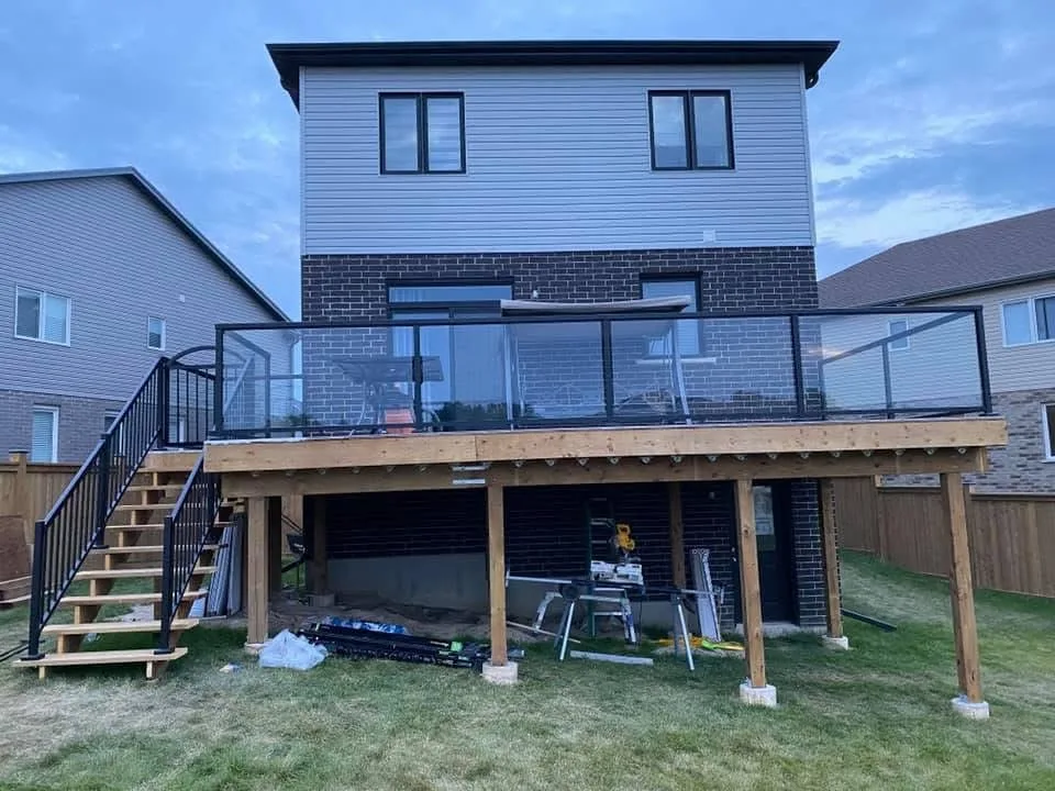 Raised backyard deck with glass railing panels viewed from the lawn