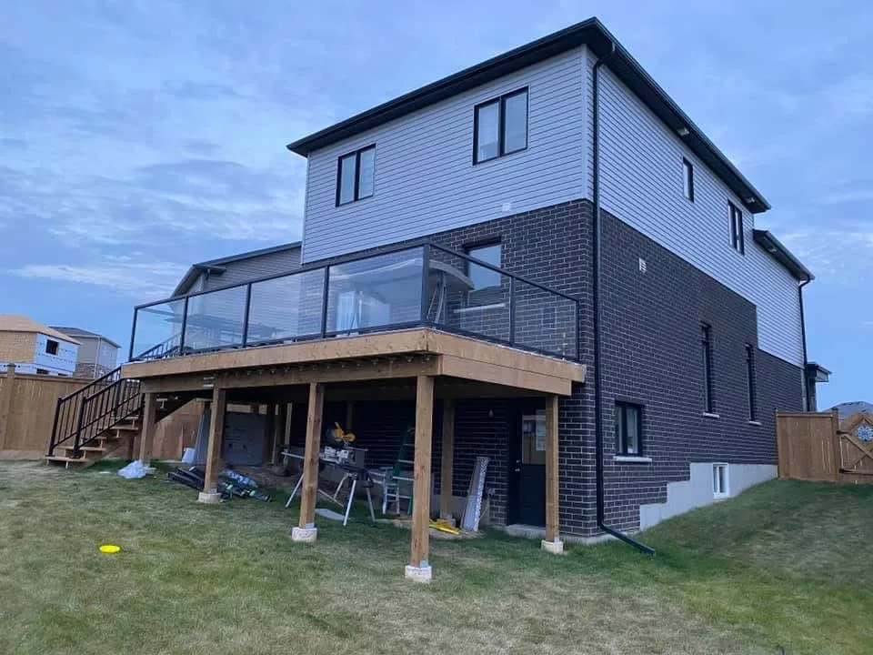 Raised wood deck with glass railing panels and stairs to the backyard